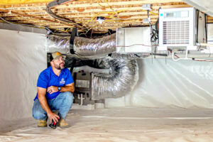A worker inspecting a newly encapsulated crawl space with a dehumidifier installed by Stay Dry Waterproofing LLC in Marysville, OH.