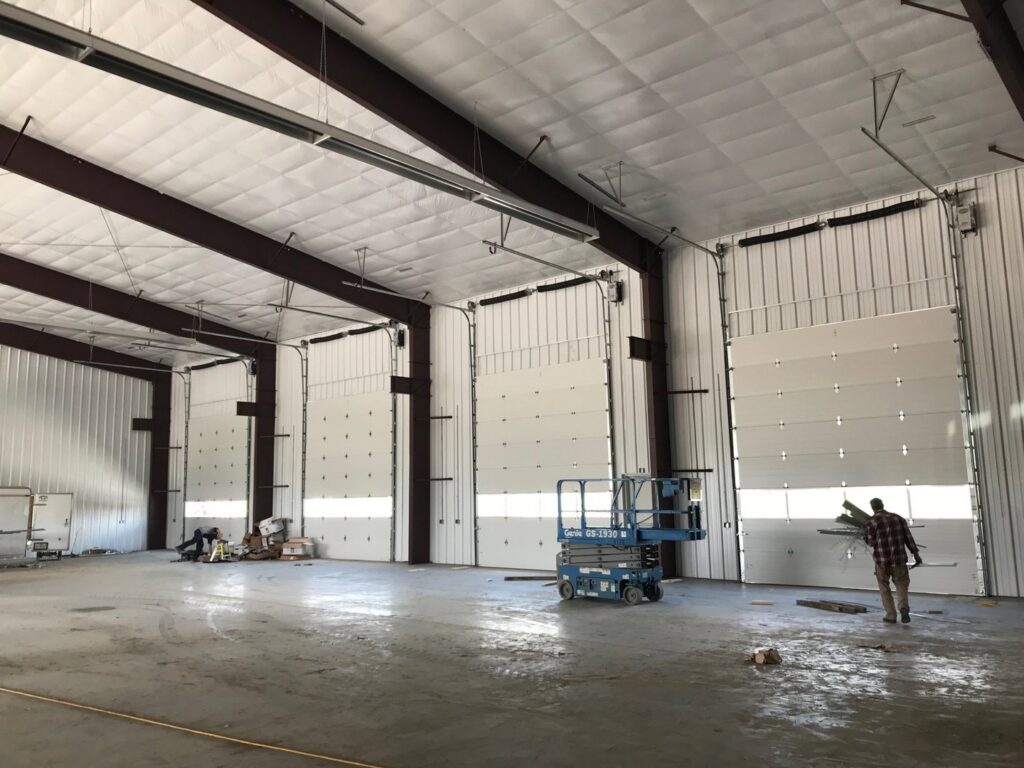 A worker installing or servicing commercial overhead doors inside a large facility by Elite Door in Winchester, CA.