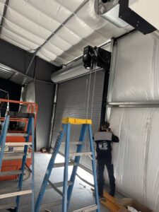 A worker installing a commercial roll-up garage door, a service provided by Barrett Overhead Doors in Idaho Falls, ID.