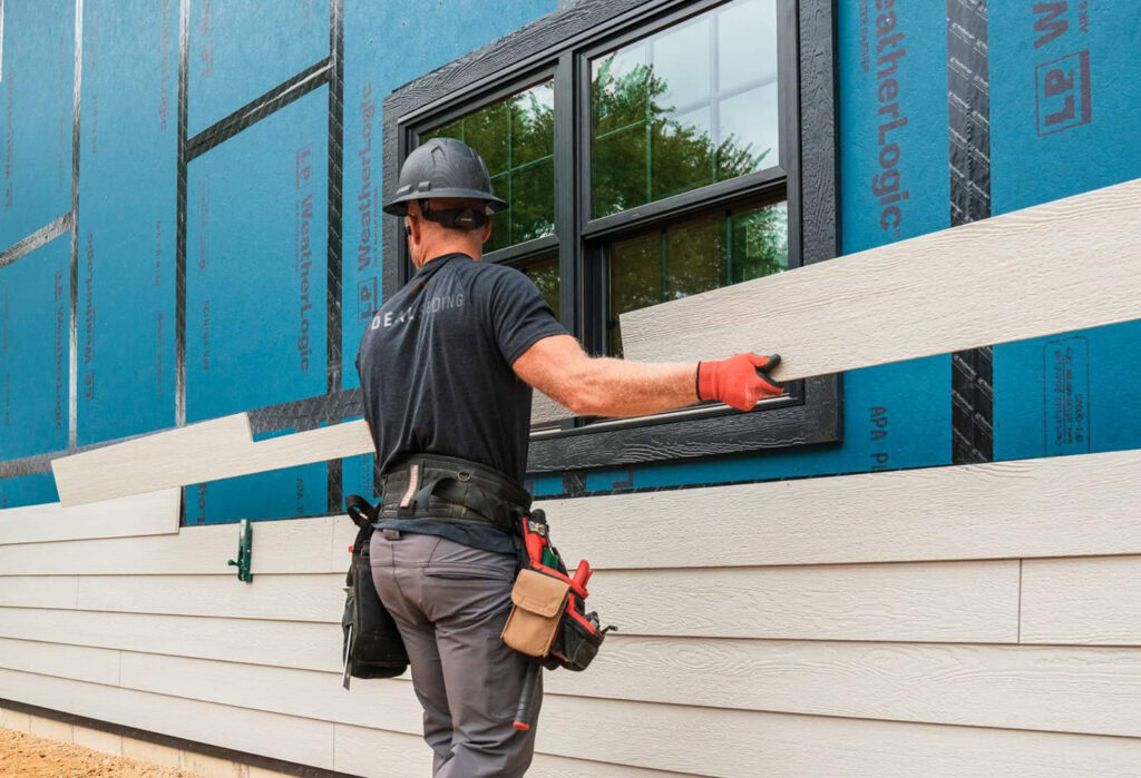 A professional worker installing new siding panels on a house, showcasing the expertise of Ideal Siding Nashville, TN.