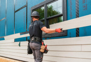 A professional worker installing new siding panels on a house, showcasing the expertise of Ideal Siding Nashville, TN.