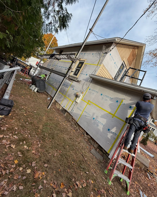 A worker installing new siding on a house for J&J Rivera Roofing and Supply Co in Old Saybrook, CT