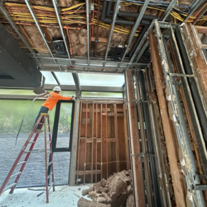 A worker on a ladder performing interior stripping and demolition for DEMO Leaders in Los Angeles, CA