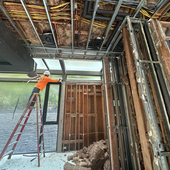 A worker on a ladder performing interior stripping and demolition for DEMO Leaders in Los Angeles, CA
