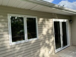 A worker on a ladder installing gray vertical siding on a house, by DJ Paz All Siding & Roofing Construction in Iowa City, IA