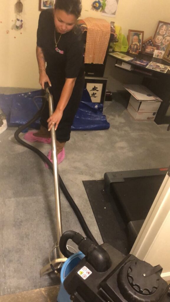 A worker performing water extraction from a carpeted floor using professional equipment for Restoration 1 of OKC in Yukon, OK.