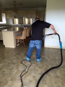 A worker performing water extraction on a tiled kitchen floor using professional equipment for Restoration 1 of OKC in Yukon, OK.