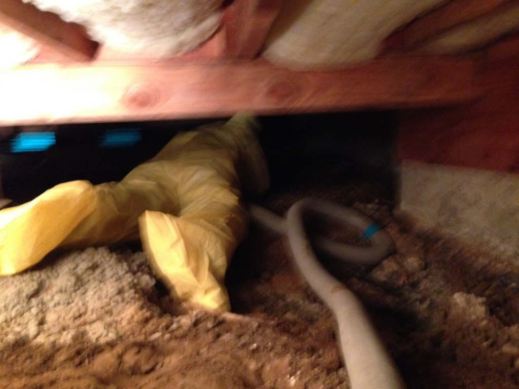 A worker in a yellow protective suit performing water damage remediation in a crawl space for San jose water damage in San Jose, CA