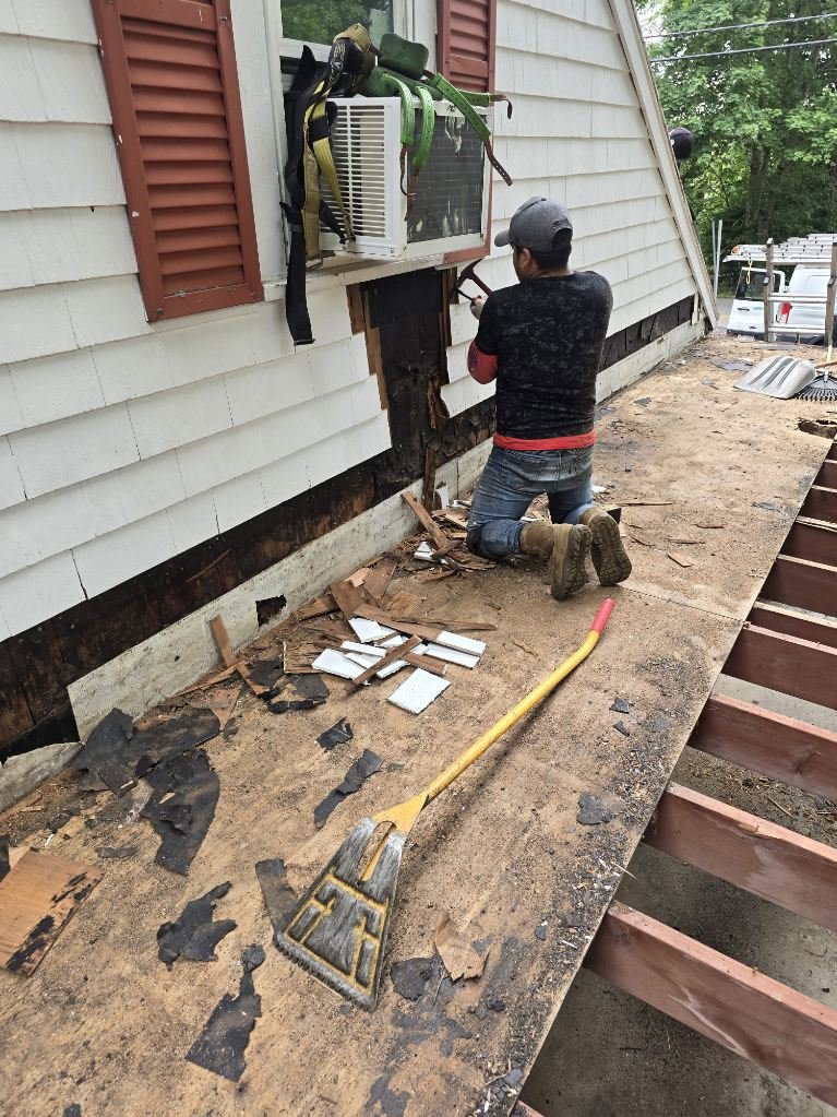 A worker removing old siding from a house during a renovation project by Pride Exteriors in North Attleborough, MA.