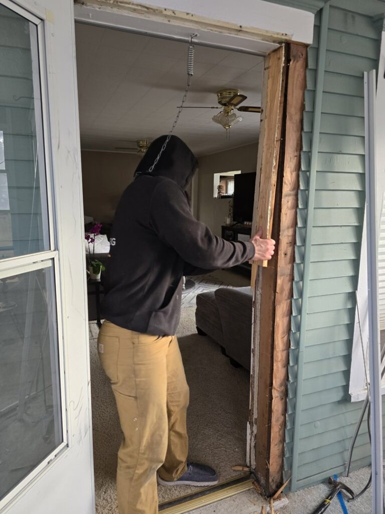 A worker from Grand Rising Group removing a water-damaged door frame during a restoration project in Mitchell, SD.