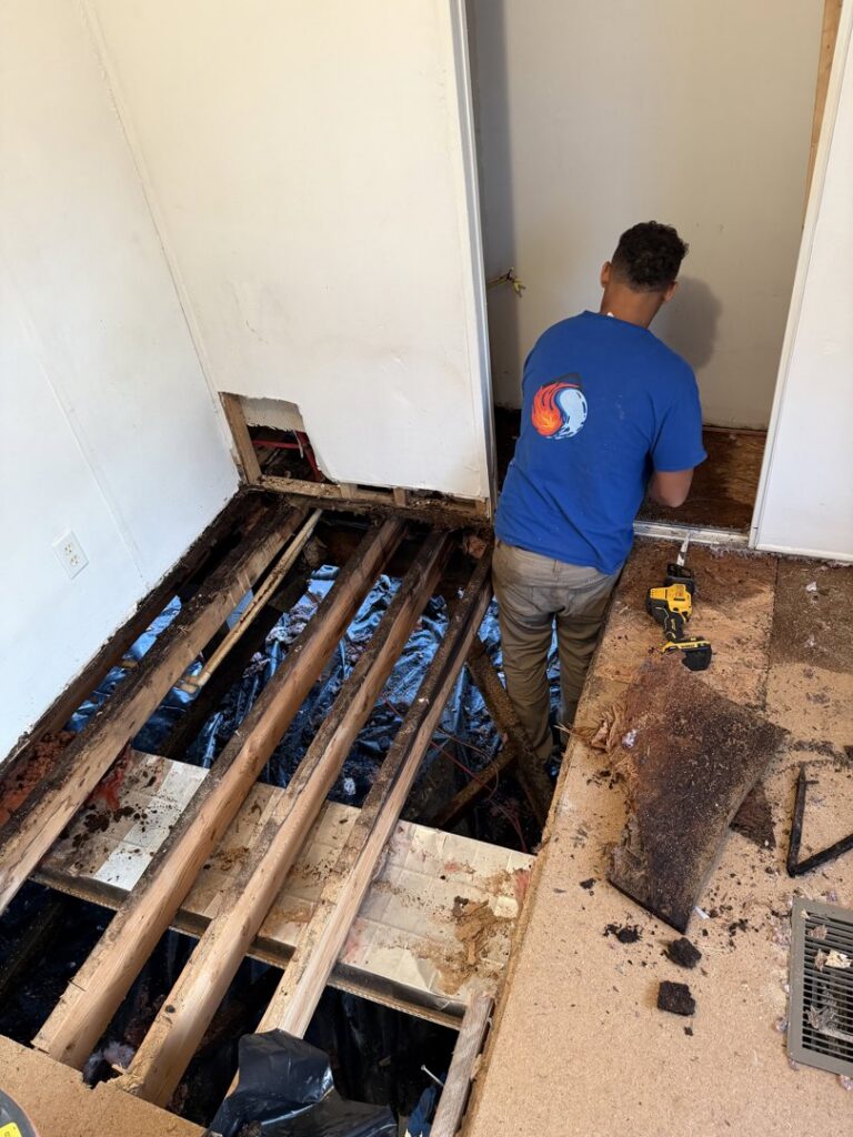 A restoration worker removing water-damaged flooring to expose the subfloor for Prime Restoration in Lancaster, PA.