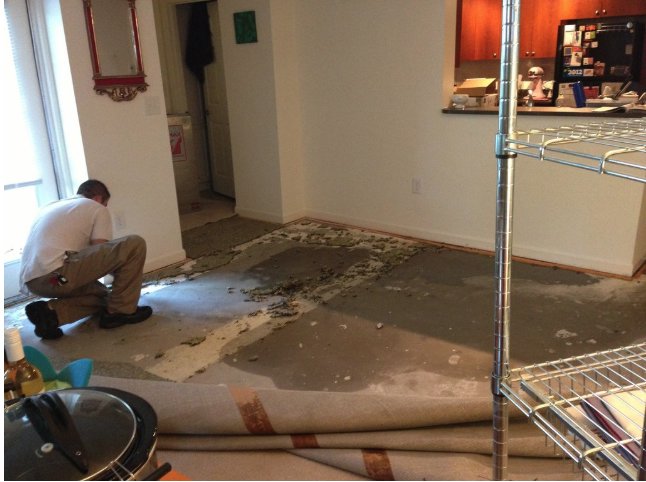 A worker removing wet carpet and flooring to reveal a damp subfloor, a water damage restoration task by SO-CO Water Damage in Pueblo, CO.