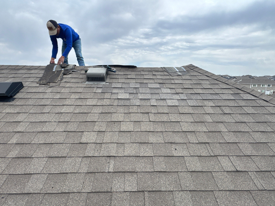 A worker repairing damaged roof shingles to prevent water leaks for Sharp Restoration in Lincoln, NE.