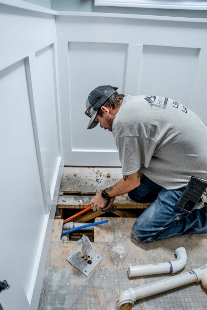 A Home Care & Repair specialist repairing pipes under a floor, a common task in water damage restoration, in Lafayette, IN.