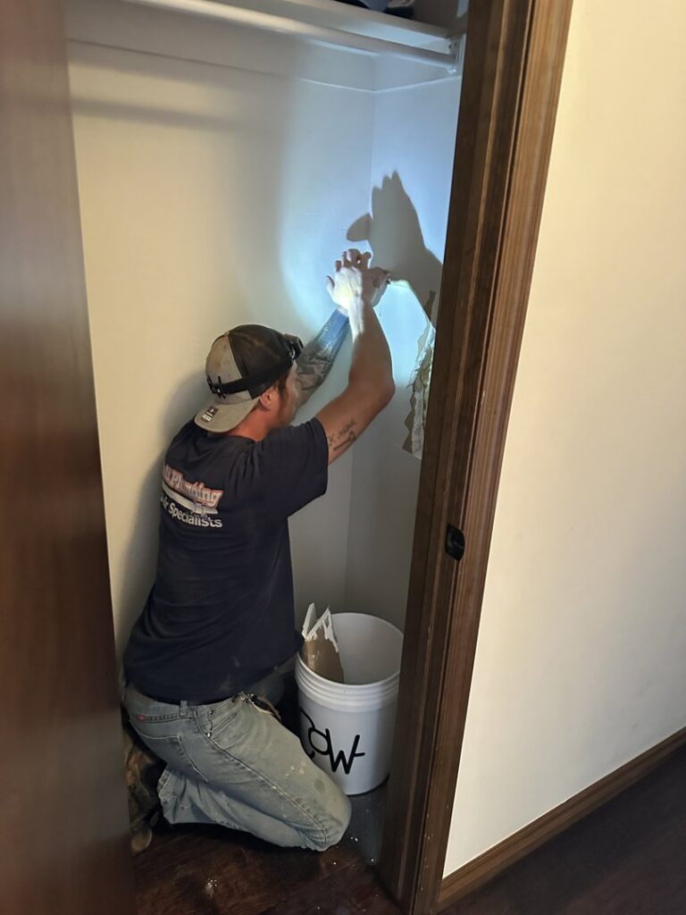 A Hull Plumbing, Inc. worker repairing a water-damaged wall in a closet in Oklahoma City, OK.