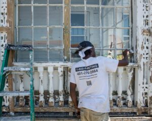 A worker repairing a severely water-damaged window frame on a building exterior for LOPCO Contracting in Johnston, RI.