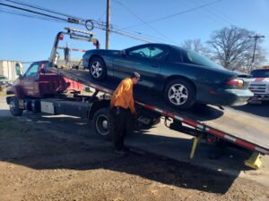 A worker securing a green sports car onto a flatbed tow truck for Craig's Towing & Recovery in New Castle, DE.