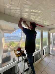 A Rescue One Restoration worker setting up plastic containment sheeting on a ceiling during a water damage job in Honolulu, HI.