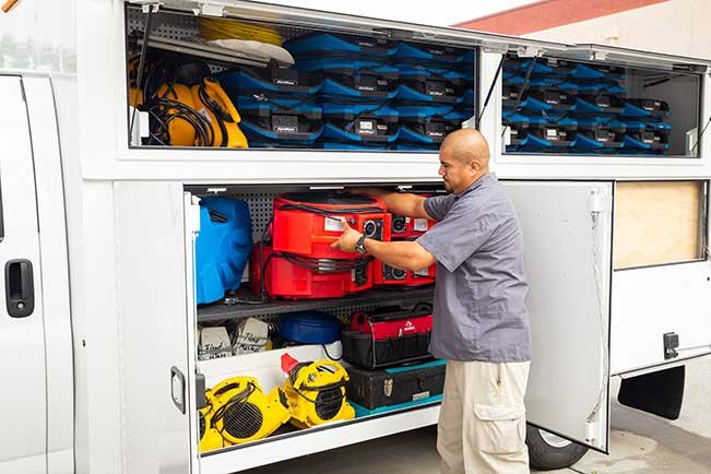 A Certified Restoration worker unloading specialized water damage drying equipment from a service truck in San Diego, CA