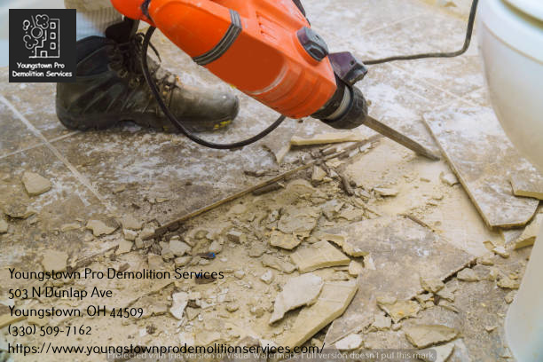 A worker using a jackhammer to remove old floor tiles, an interior demolition service by Youngstown Pro Demolition Services in Youngstown, OH.