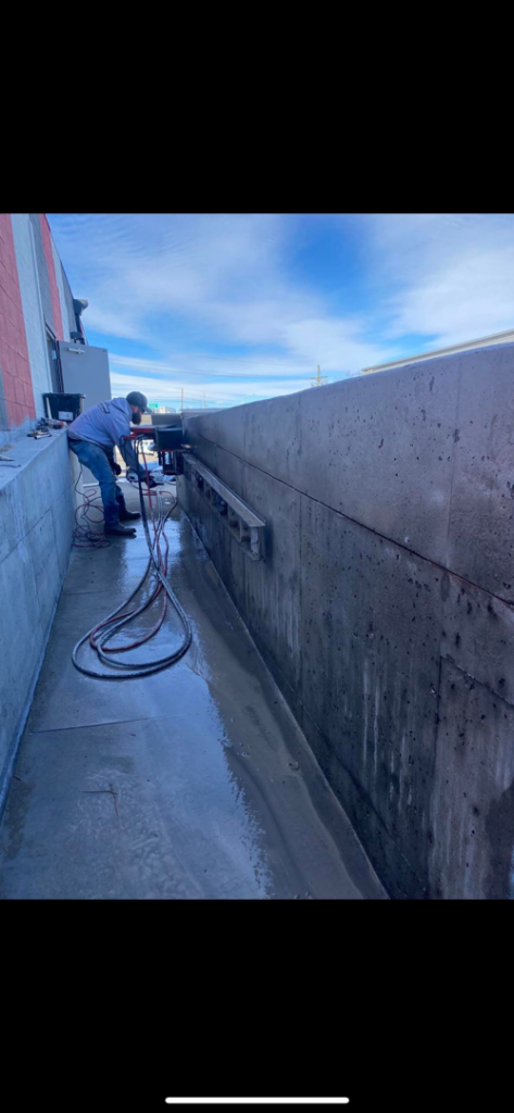 A worker from Independent Concrete Cutter Corp. using a wall saw to precisely cut a concrete wall in Denver, CO.