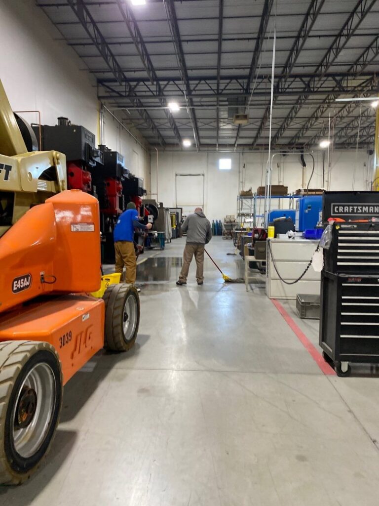Workers cleaning a wet industrial floor after water damage for Guardian Angel Restoration in Noblesville, IN