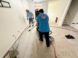 Two Minutemen Property Damage Services workers extracting water from a carpeted floor during a water damage job in North Charleston, SC.