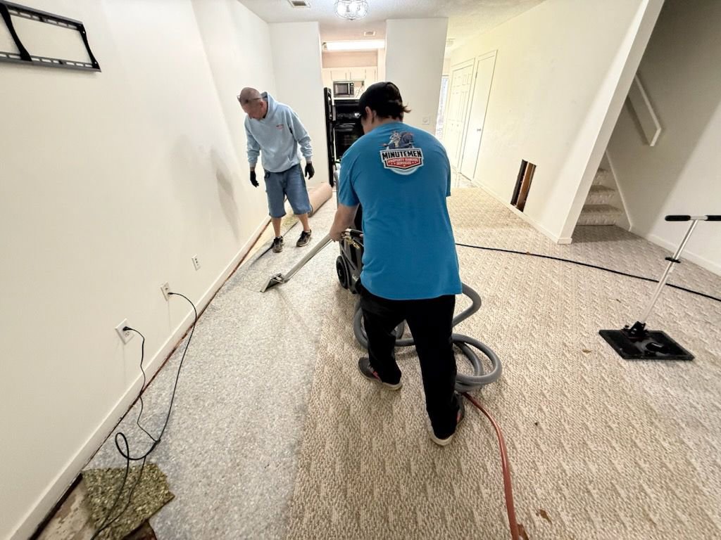 Two Minutemen Property Damage Services workers extracting water from a carpeted floor during a water damage job in North Charleston, SC.