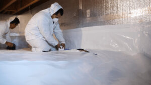 Two workers installing a crawl space vapor barrier for Waterdry Indiana in South Bend, IN