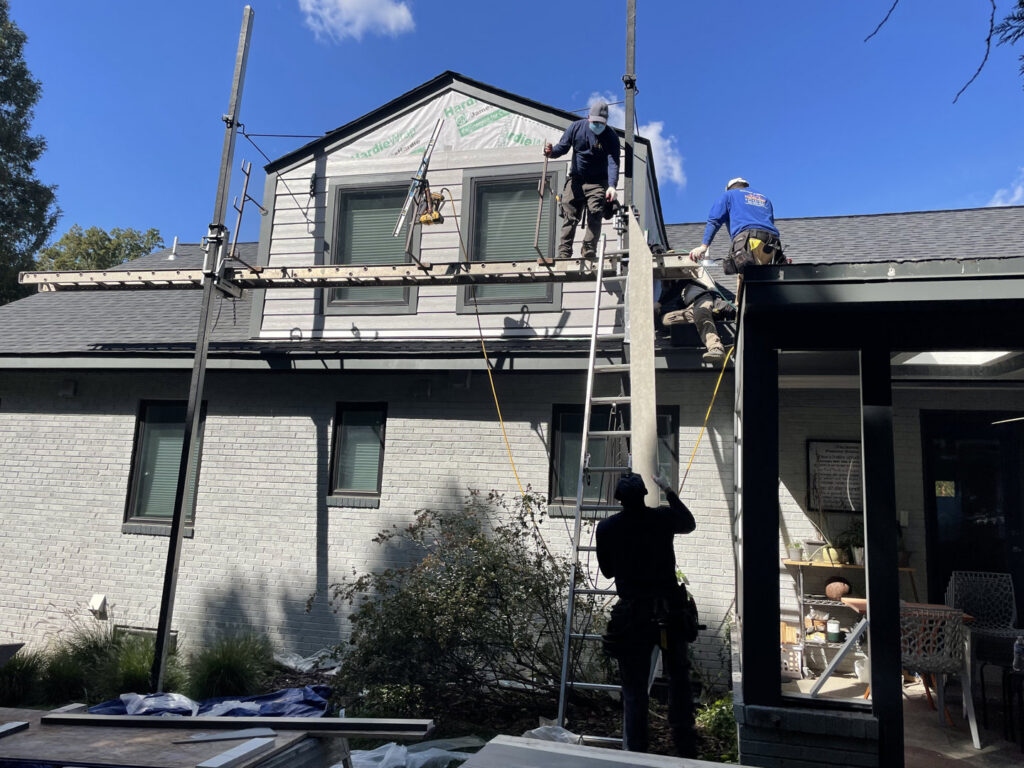 Skilled workers installing gray horizontal siding on a house using scaffolding by High Quality Exteriors in Rockville, MD.