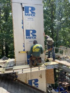 Workers installing R-MAX insulation boards on a chimney chase, part of exterior work by JHV Roofing in Scranton, PA.