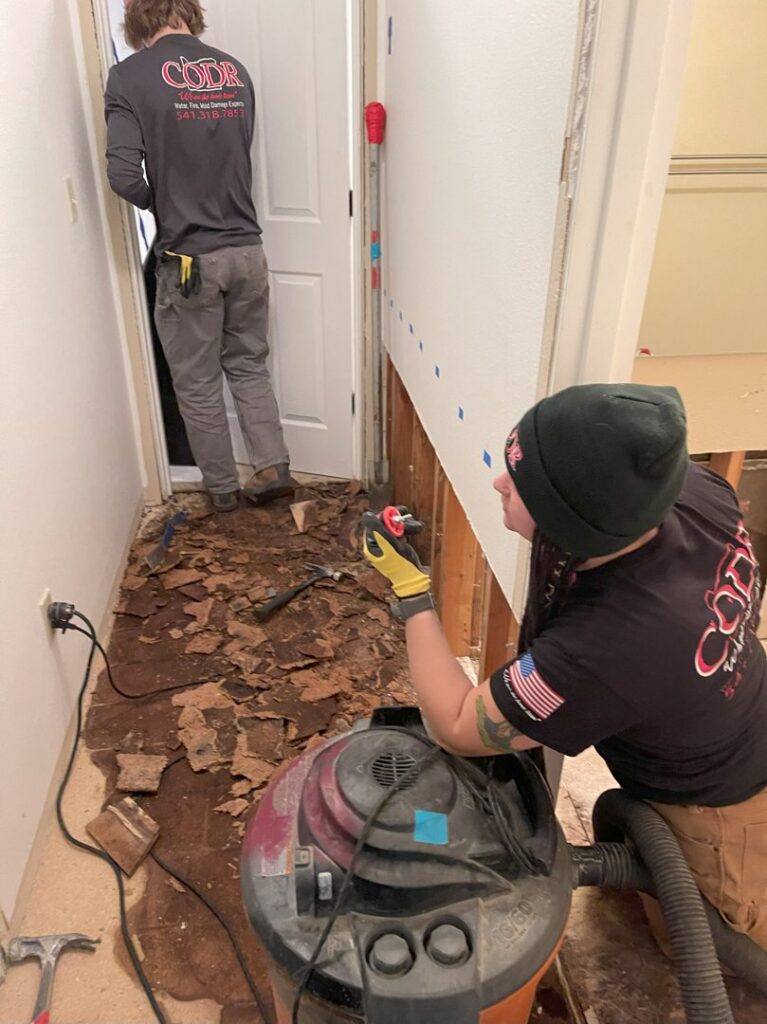Workers removing water-damaged flooring and drywall, a service provided by Central Oregon Disaster Restoration in Bend, OR.