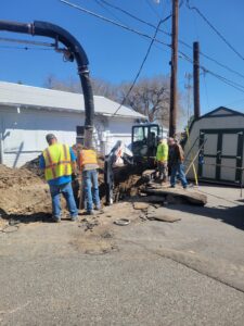 Workers repairing an underground water line with a vacuum excavator and mini excavator for B&M Septic and Excavation Services in Riverton, WY