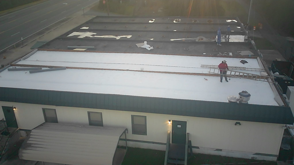 Workers actively tearing off an old commercial roof for MasterMind Construction in Shiloh, GA.