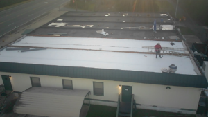 Workers actively tearing off an old commercial roof for MasterMind Construction in Shiloh, GA.