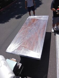 A large, wrapped dining table ready for loading onto a moving truck by Rough Çutt Movers in San Diego, CA