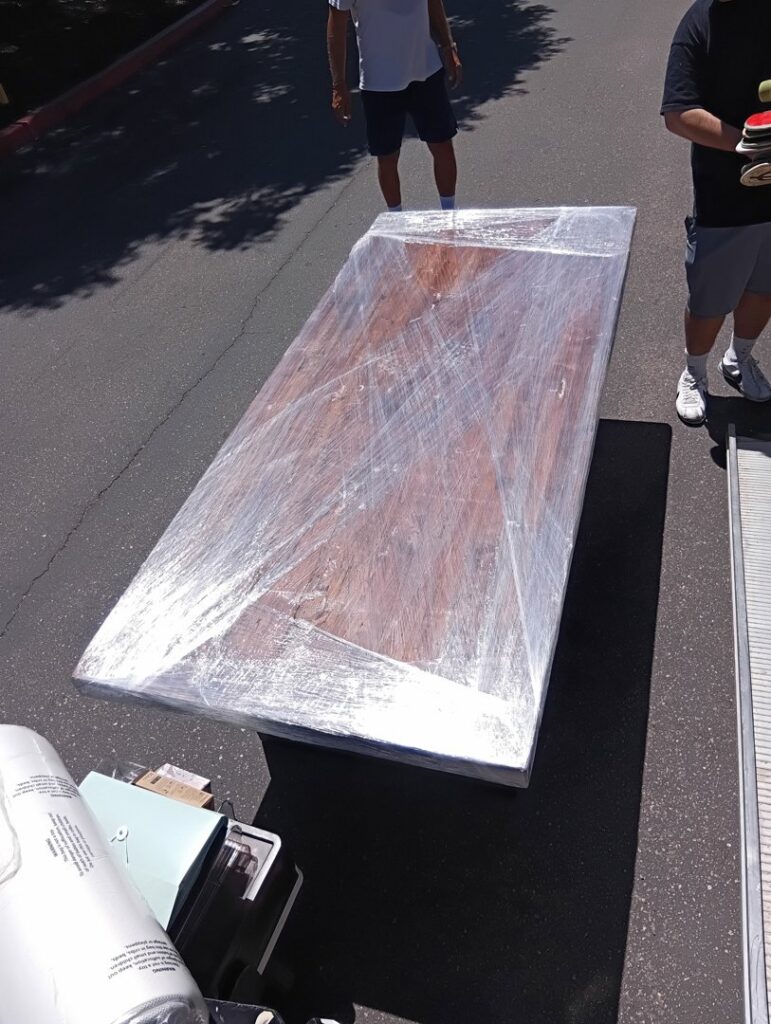 A large, wrapped dining table ready for loading onto a moving truck by Rough Çutt Movers in San Diego, CA