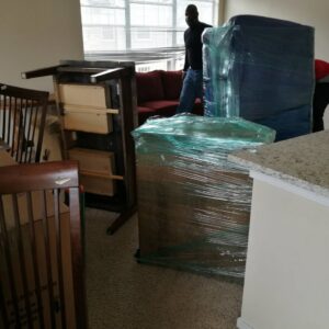 Wrapped furniture and a mover preparing items inside a home for allpromovingservice in San Antonio, TX.