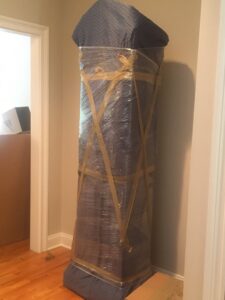 A tall piece of furniture, securely wrapped and taped by Mastodon Moving LLC, ready for transport in Westborough, MA.