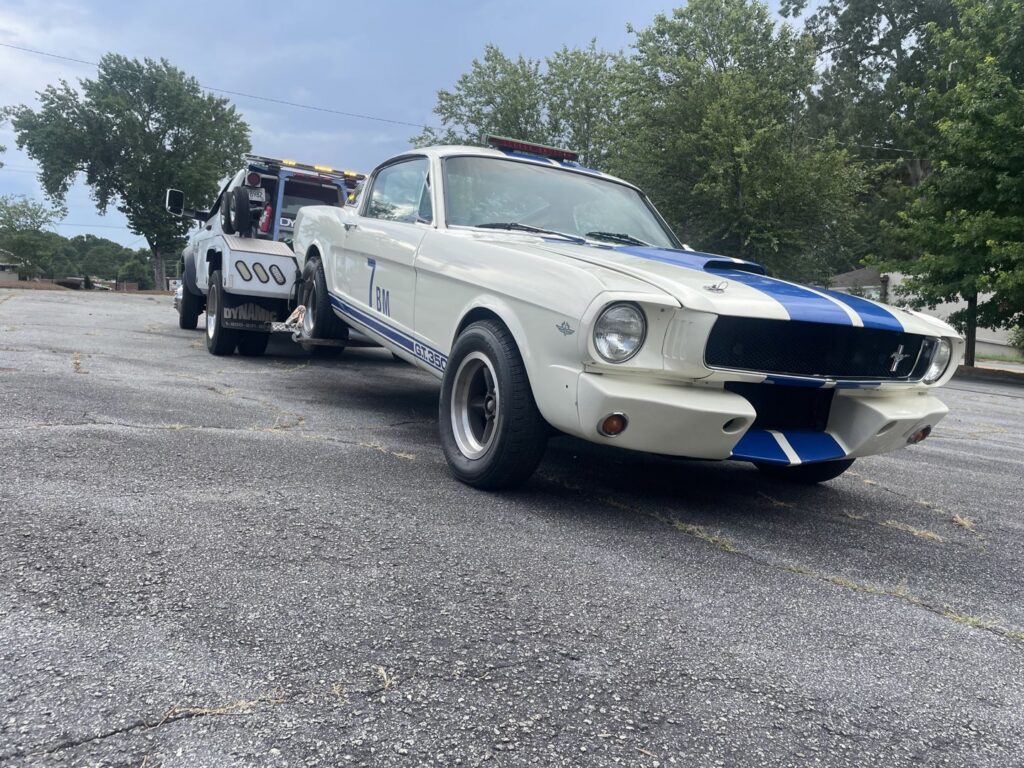 A white wrecker tow truck from Andre's Towing Services, LLC towing a classic white Mustang in Marietta, GA.