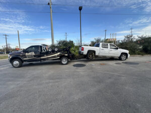 A wrecker tow truck from Rosco's Towing Services LLC towing a white pickup truck in Carencro, LA.
