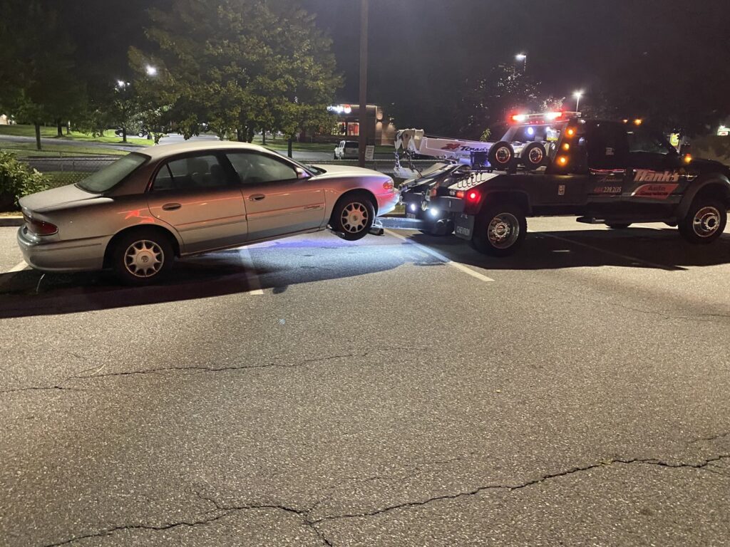 A white wrecker tow truck from Hank's Auto Service towing a silver sedan at night in Bethlehem, PA.