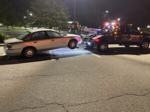 A white wrecker tow truck from Hank's Auto Service towing a silver sedan at night in Bethlehem, PA.