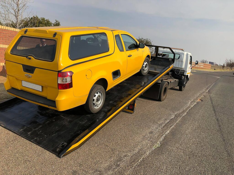 A yellow car being transported on a flatbed tow truck by Cities Superior Towing Corp. in Lake Charles, LA.