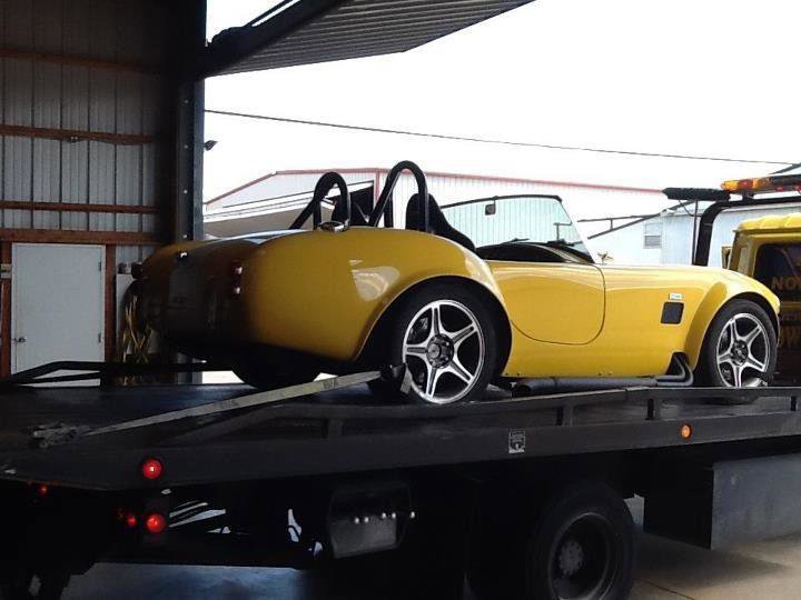A yellow classic convertible car loaded onto a Tow Jam flatbed tow truck in Dallas, TX.
