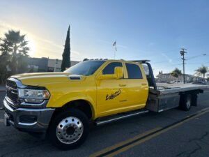 A bright yellow flatbed tow truck from Ledesma's Towing parked on a street in San Diego, CA.