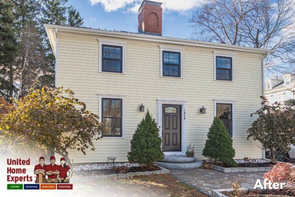 A classic yellow house with new siding and contrasting black trim, completed by United Home Experts in Ashland, MA