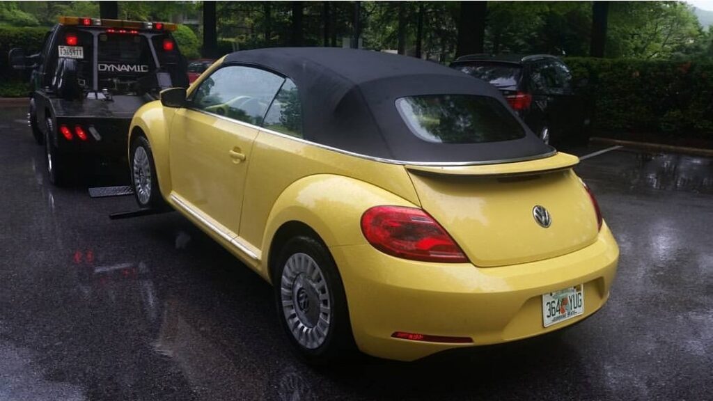 A yellow Volkswagen Beetle convertible being towed by Whitelock Towing in Baltimore, MD.