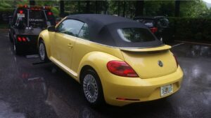 A yellow Volkswagen Beetle convertible being towed by Whitelock Towing in Baltimore, MD.