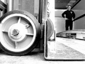 A close-up of a hand truck wheel with a mover in the background inside a Your Friends - Moving Services truck in Lansing, MI.